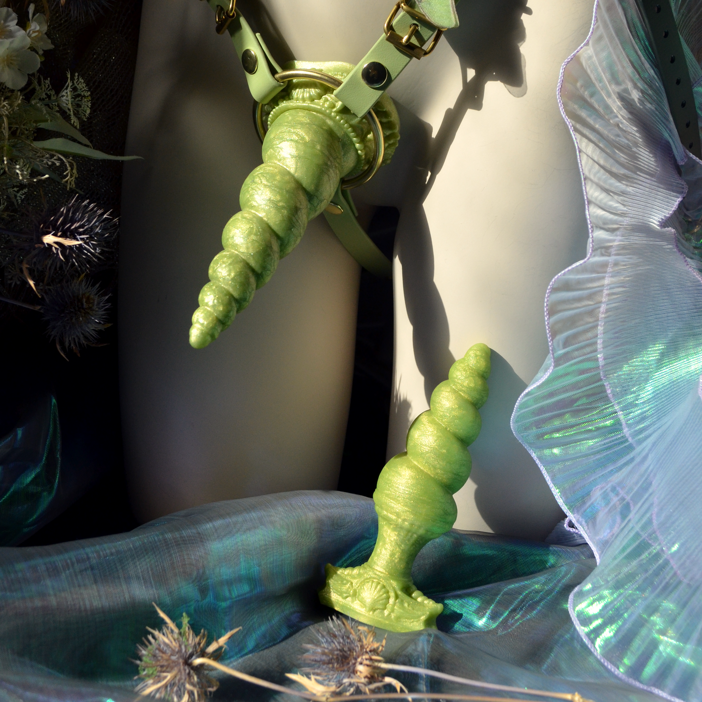 Dildo fantasy dans un harnais de type Strap-On vert idéal pour du pegging. Un dildo licorne en silicone de Fera Daemon.