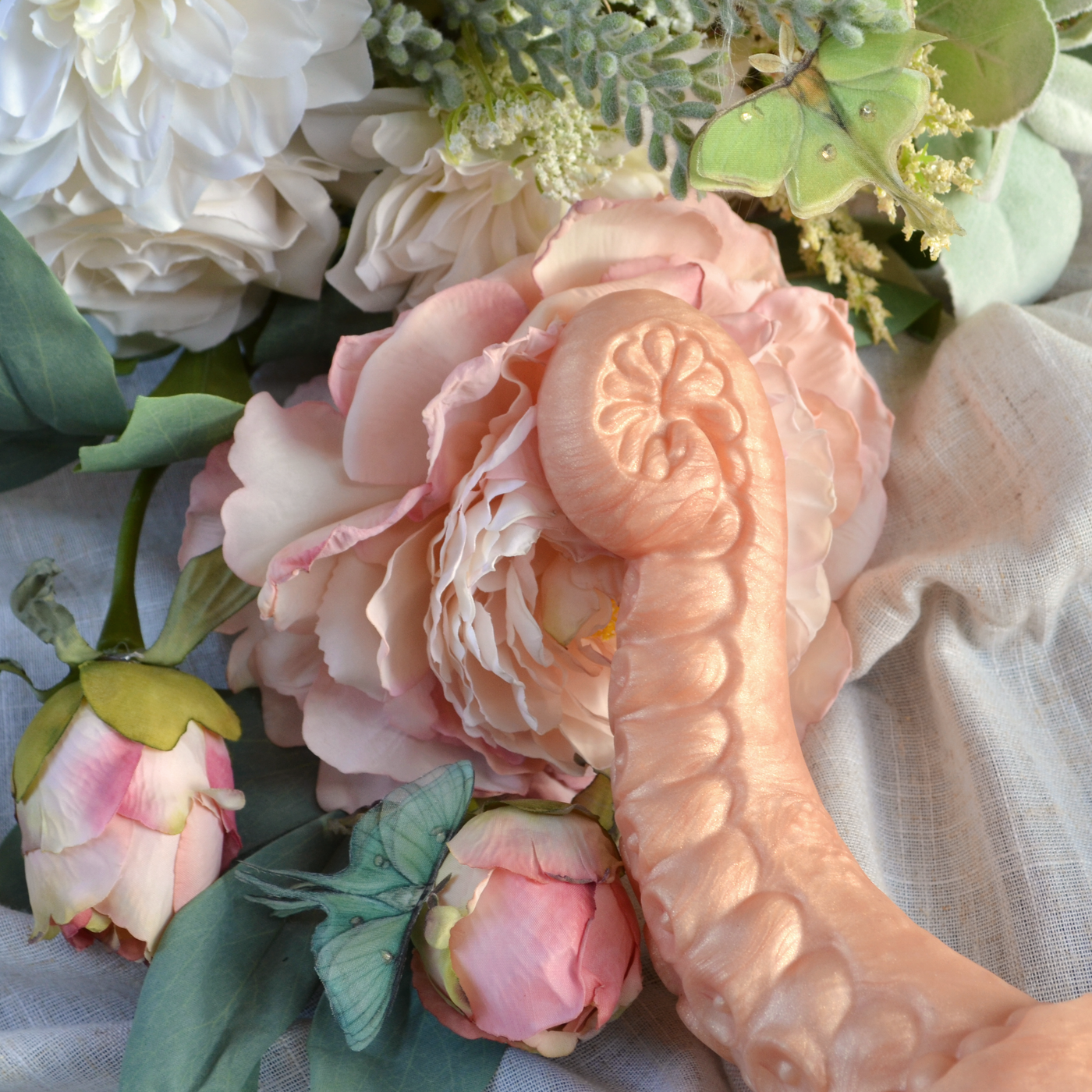 Le dildo tentacule Néa Enroulée dans le coloris pèche Pivoine Nacrée, un sextoy texturé en silicone médical