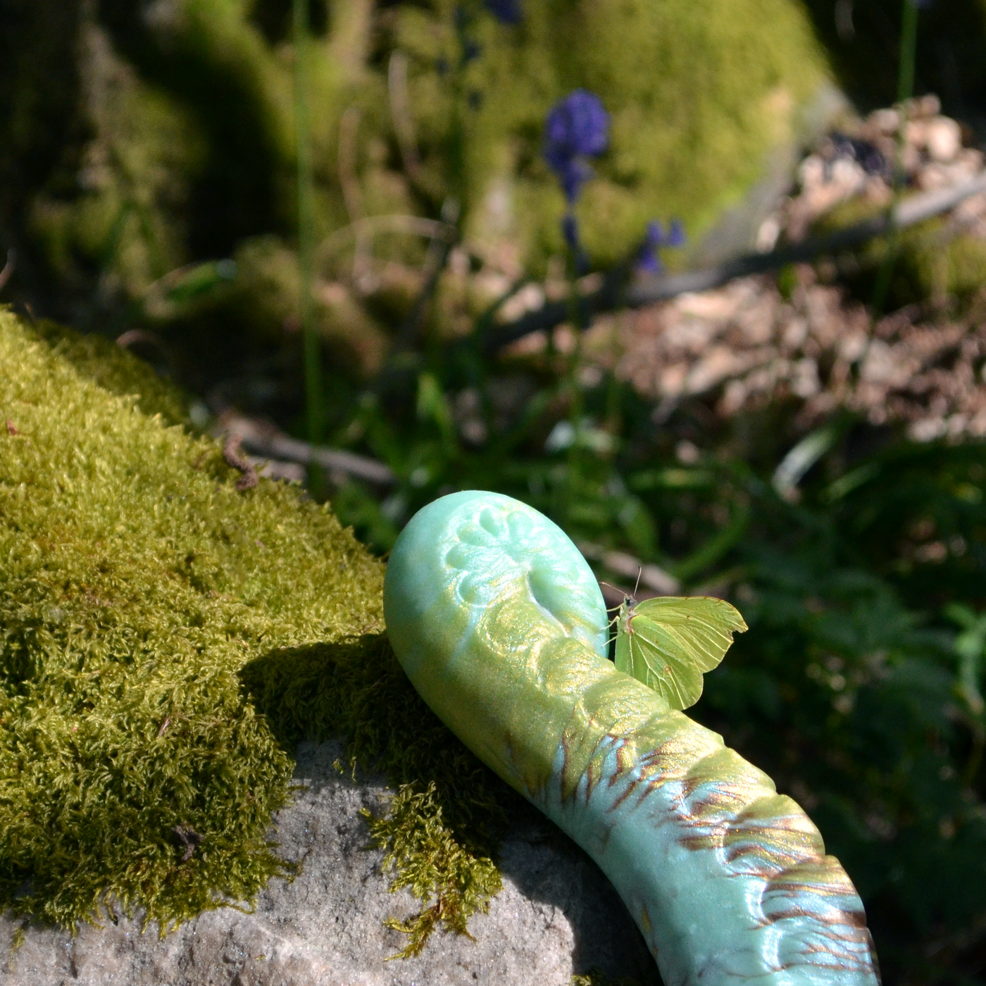 Dildo tentacule vert de Fera Daemon inspiré de la nature et de l'esthétique elfique. Photo en forêt avec un papillon.