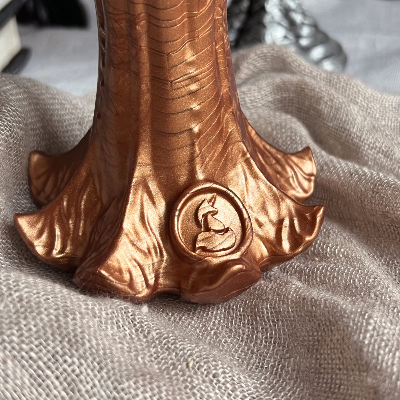 Logo de la marque Fera Daemon sur la base d'un sextoy Nymf en silicone cuivré