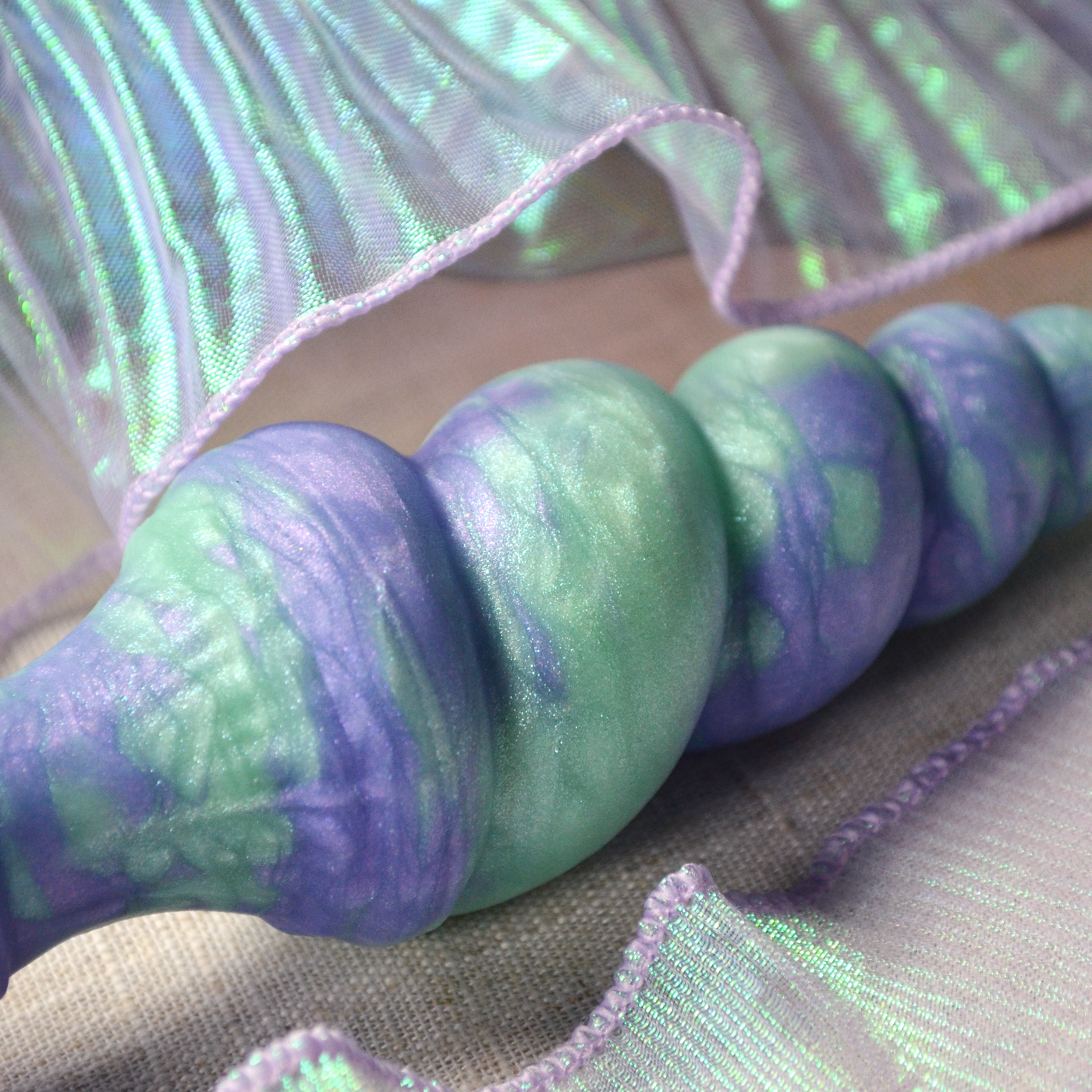 Nacres dans le silicone vert d'eau et violet pastel du sextoy torsadé en forme de corne de licorne Fênra Plug.