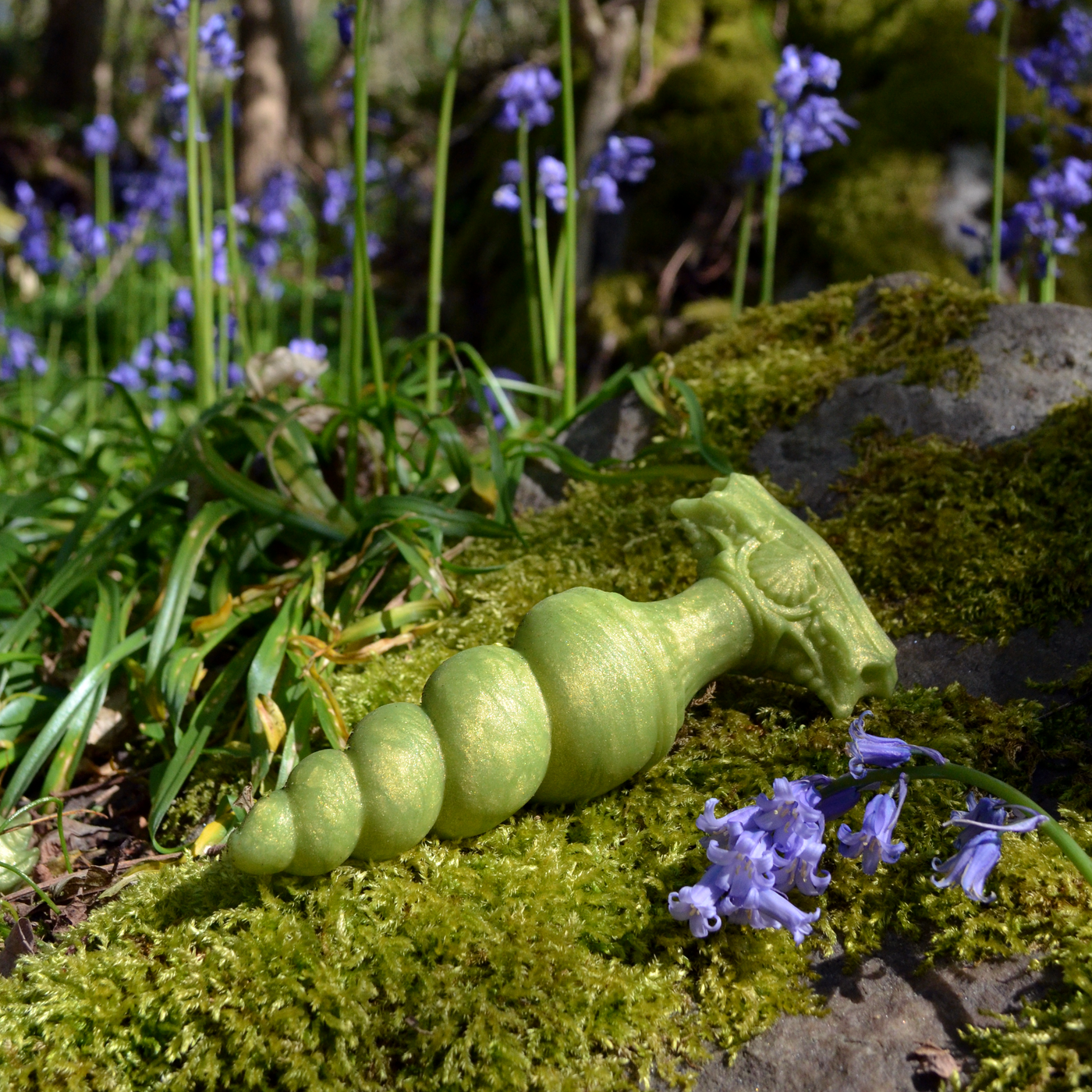 Plug anal avec une forme progressive et torsadée inspirée d'une corne de licorne. Un plug fantasy en silicone vert pomme dans la nature.